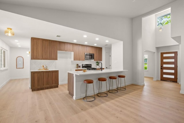 12303 Turtleback Ln, Austin, TX 78727 - kitchen featuring stainless steel appliances, brown cabinetry, light countertops, light wood-style flooring, and decorative backsplash