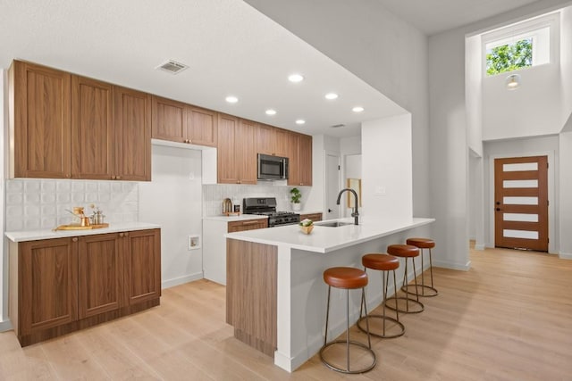 12303 Turtleback Ln, Austin, TX 78727 - kitchen with stainless steel appliances, brown cabinets, light wood-style flooring, backsplash, and recessed lighting