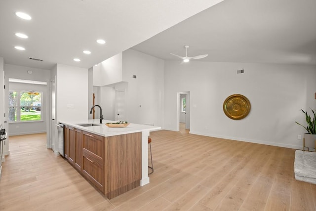 12303 Turtleback Ln, Austin, TX 78727 - kitchen featuring brown cabinets, light wood-type flooring, open floor plan, an island with sink, and ceiling fan