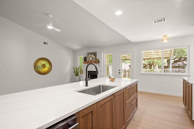 12303 Turtleback Ln, Austin, TX 78727 - kitchen with a large fireplace, light countertops, light wood-type flooring, brown cabinetry, and vaulted ceiling