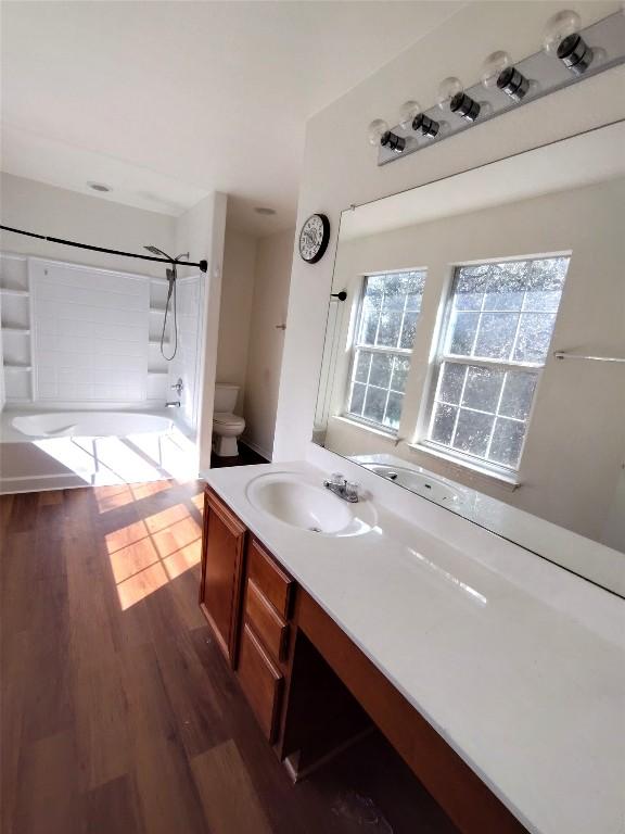 2108 Cottontail Dr, Leander, TX 78641 - bathroom with toilet, washtub / shower combination, vanity, and wood finished floors