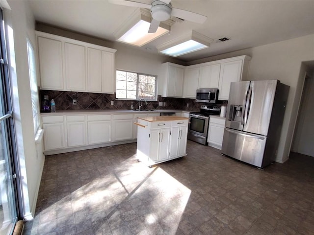 2108 Cottontail Dr, Leander, TX 78641 - kitchen with stainless steel appliances, a sink, a center island, ceiling fan, and backsplash