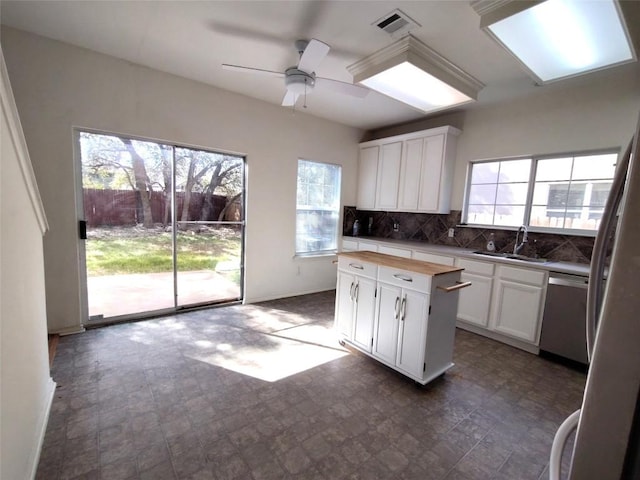 2108 Cottontail Dr, Leander, TX 78641 - kitchen featuring a sink, stainless steel dishwasher, wood counters, white cabinetry, and decorative backsplash