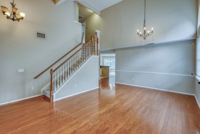 6429 Clay Allison Pass, Austin, TX 78749 - unfurnished living room featuring a chandelier, a high ceiling, stairway, wood finished floors, and baseboards