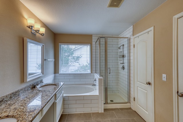 6429 Clay Allison Pass, Austin, TX 78749 - full bathroom featuring tile patterned floors, healthy amount of natural light, double vanity, a textured ceiling, and a bath