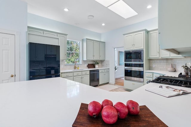 6008 Woodview Ave, Austin, TX 78757 - kitchen with black appliances, decorative backsplash, recessed lighting, light countertops, and a skylight
