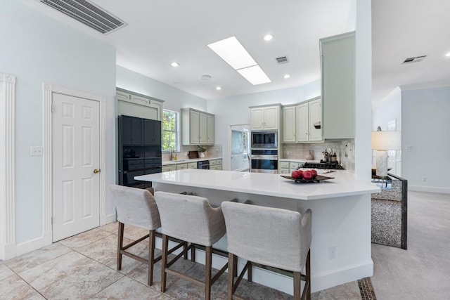 6008 Woodview Ave, Austin, TX 78757 - kitchen featuring black appliances, a peninsula, tasteful backsplash, a breakfast bar, and light countertops