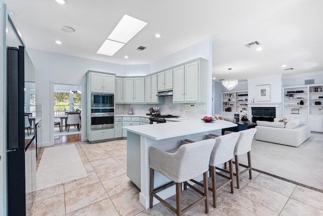 6008 Woodview Ave, Austin, TX 78757 - kitchen with appliances with stainless steel finishes, a peninsula, a kitchen bar, under cabinet range hood, and light countertops