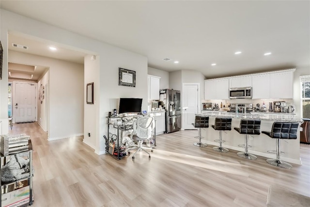 3204 Mount Vernon Ave, Lago Vista, TX 78645 - kitchen with stainless steel appliances, light wood-style flooring, a kitchen breakfast bar, recessed lighting, and white cabinets