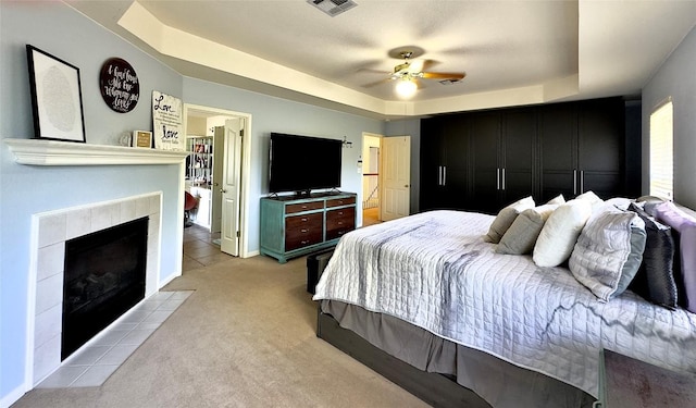 404 Autumn Trl, Georgetown, TX 78626 - bedroom featuring a raised ceiling, a fireplace, light colored carpet, a ceiling fan, and light tile patterned floors