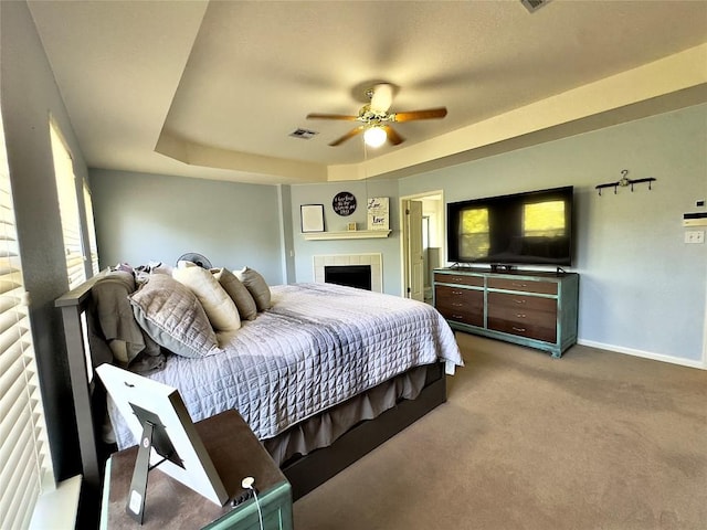 404 Autumn Trl, Georgetown, TX 78626 - carpeted bedroom with baseboards, a tiled fireplace, a raised ceiling, and a ceiling fan