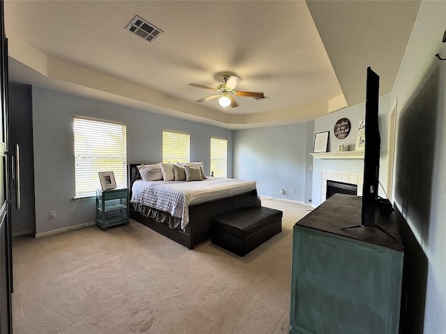 404 Autumn Trl, Georgetown, TX 78626 - bedroom with a tray ceiling, light colored carpet, a tiled fireplace, and multiple windows