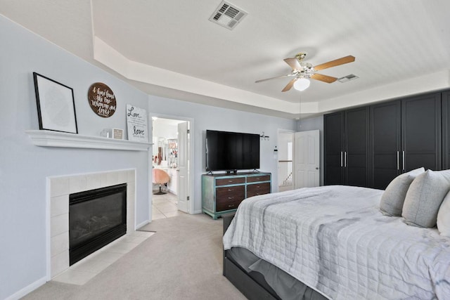 404 Autumn Trl, Georgetown, TX 78626 - bedroom with light carpet, ensuite bathroom, a tiled fireplace, a tray ceiling, and ceiling fan