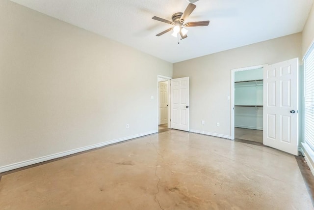 518 Clear Creek Ln, Dripping Springs, TX 78620 - unfurnished bedroom featuring finished concrete flooring, a walk in closet, baseboards, a closet, and a ceiling fan