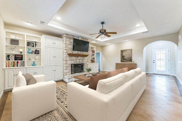 518 Clear Creek Ln, Dripping Springs, TX 78620 - living room featuring a tray ceiling, ceiling fan, arched walkways, a stone fireplace, and recessed lighting
