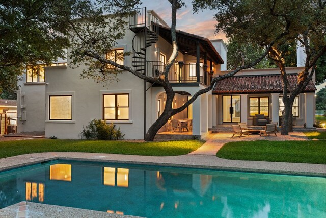 4622 Lake View Dr, Austin, TX 78731 - back of property at dusk with a balcony, stucco siding, an outdoor pool, and a patio