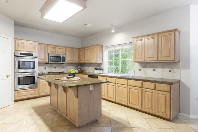 10701 Redmond Rd, Austin, TX 78739 - kitchen featuring appliances with stainless steel finishes, tasteful backsplash, light brown cabinetry, and a kitchen island