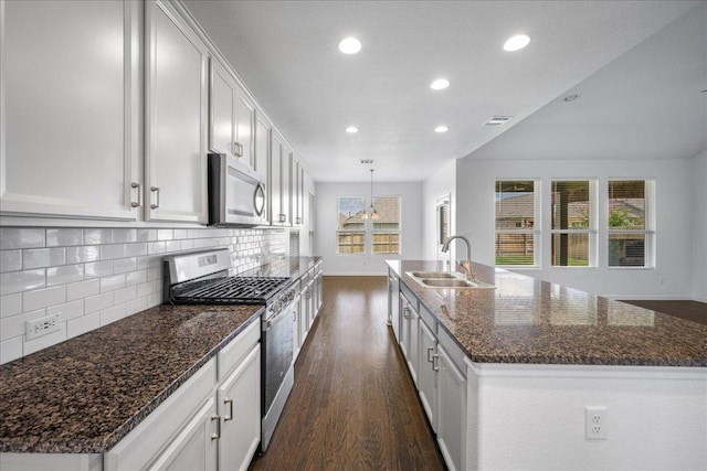 1013 S San Marcos St, Manor, TX 78653 - kitchen with stainless steel appliances, recessed lighting, dark wood-style flooring, tasteful backsplash, and a kitchen island with sink