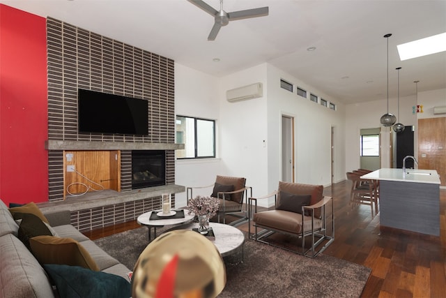 420 Starlight Village Loop Unit 17, Leander, TX 78641 - living area with a wall mounted AC, a tile fireplace, wood finished floors, a ceiling fan, and a skylight