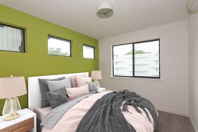 420 Starlight Village Loop Unit 17, Leander, TX 78641 - bedroom featuring multiple windows, a wall mounted AC, baseboards, and wood finished floors