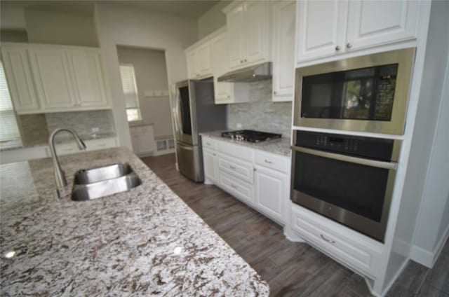 121 Bright Valley Way, Austin, TX 78737 - kitchen with stainless steel appliances, under cabinet range hood, a sink, white cabinetry, and tasteful backsplash