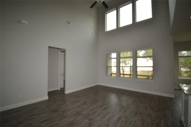 121 Bright Valley Way, Austin, TX 78737 - unfurnished living room featuring a towering ceiling, ceiling fan, plenty of natural light, baseboards, and dark wood finished floors