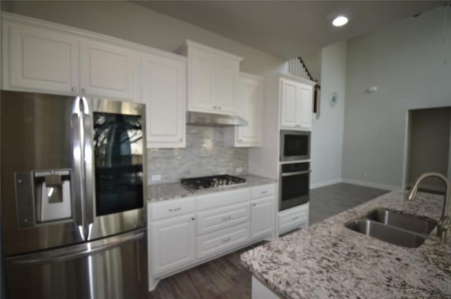 121 Bright Valley Way, Austin, TX 78737 - kitchen featuring appliances with stainless steel finishes, a sink, under cabinet range hood, backsplash, and white cabinetry