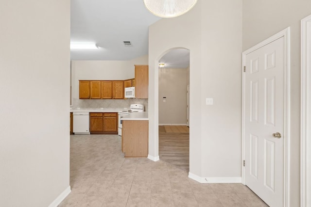 117 Kerley Dr, Hutto, TX 78634 - kitchen with white appliances, arched walkways, backsplash, light countertops, and brown cabinets