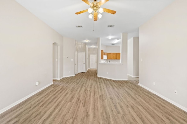 117 Kerley Dr, Hutto, TX 78634 - unfurnished living room featuring a ceiling fan, light wood-type flooring, arched walkways, and baseboards