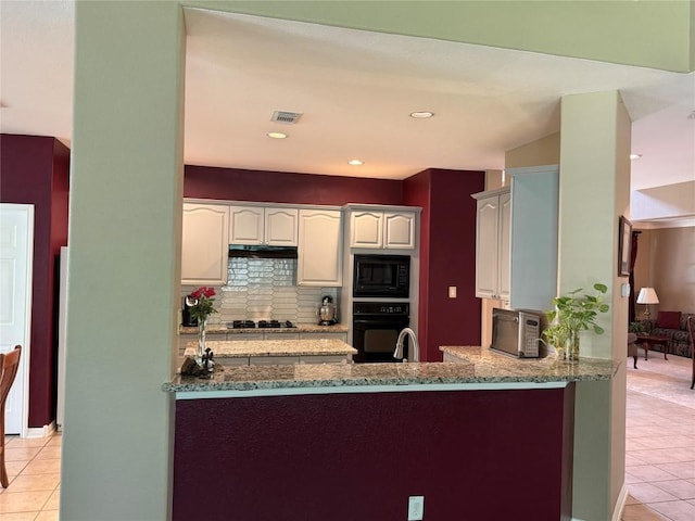 2619 Henley Dr, Round Rock, TX 78681 - kitchen with black appliances, light tile patterned floors, light stone countertops, decorative backsplash, and a peninsula