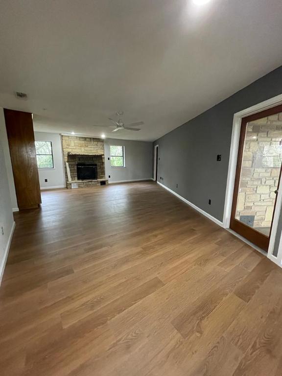 TBD County Road 246, Florence, TX 76527 - unfurnished living room featuring a ceiling fan, wood finished floors, a stone fireplace, and baseboards