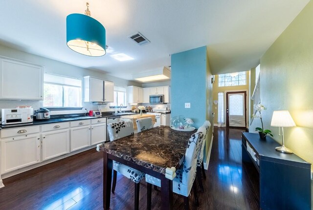 5013 Cleves St, Round Rock, TX 78681 - kitchen with stainless steel microwave, dark wood-style flooring, white cabinets, dark countertops, and hanging light fixtures