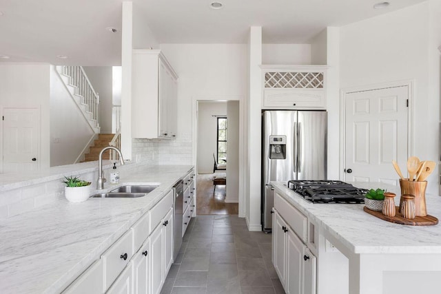 307 Malabar St, Lakeway, TX 78734 - kitchen with a sink, stainless steel appliances, white cabinetry, light stone countertops, and decorative backsplash