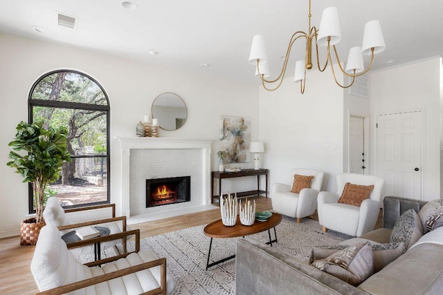 307 Malabar St, Lakeway, TX 78734 - living room with light wood-style flooring, a warm lit fireplace, and a chandelier