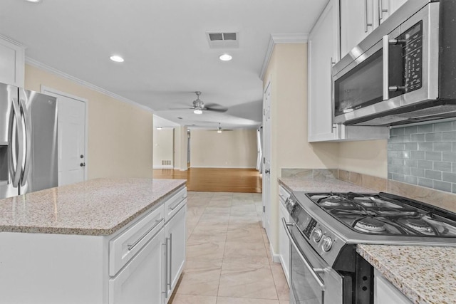 3601 Arrowhead Dr, Austin, TX 78731 - kitchen featuring appliances with stainless steel finishes, ceiling fan, crown molding, a center island, and decorative backsplash