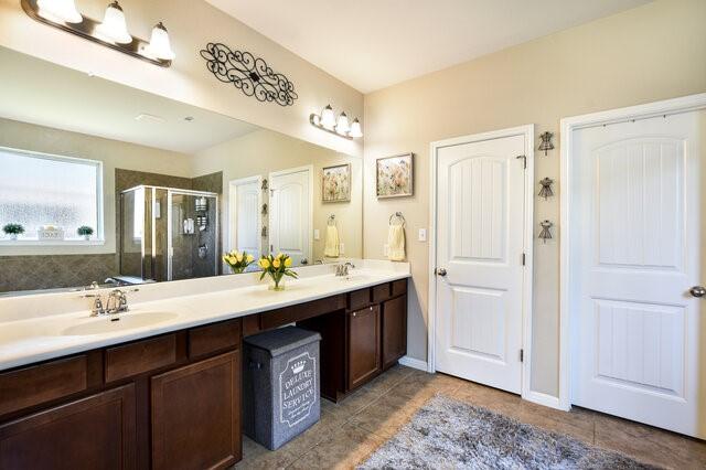 624 Purtis Creek Ln, Georgetown, TX 78628 - bathroom featuring a shower stall, double vanity, and tile patterned flooring
