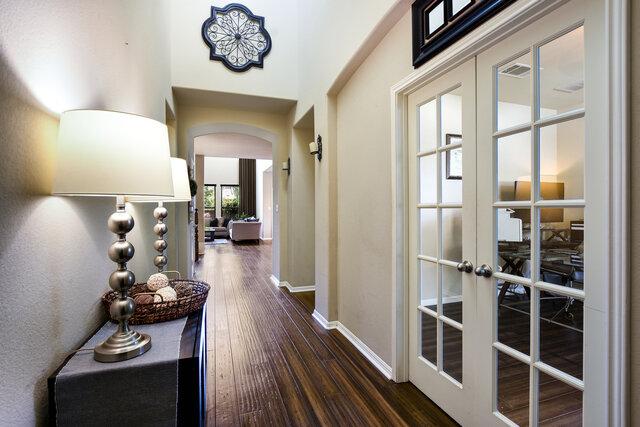 624 Purtis Creek Ln, Georgetown, TX 78628 - hall featuring arched walkways, dark wood-type flooring, french doors, and baseboards