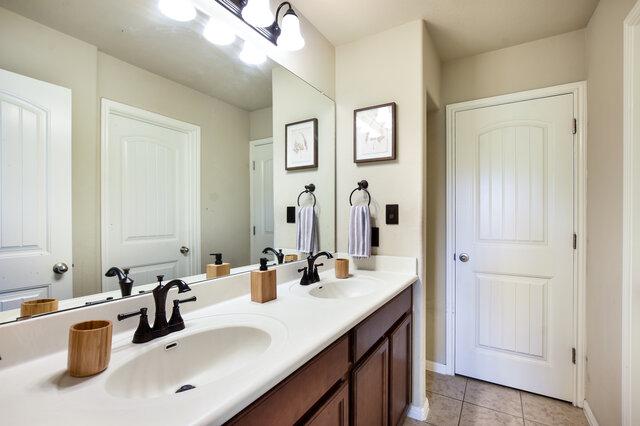 624 Purtis Creek Ln, Georgetown, TX 78628 - bathroom featuring double vanity, tile patterned floors, and baseboards