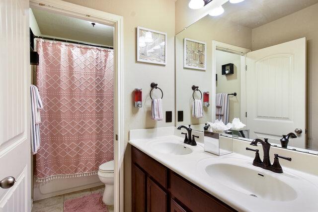 624 Purtis Creek Ln, Georgetown, TX 78628 - full bathroom featuring double vanity, toilet, tile patterned floors, and shower / bath combo with shower curtain