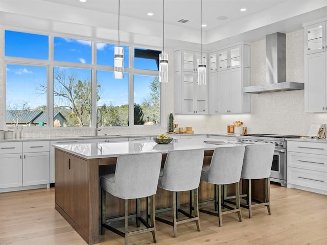 1047 Overlook Pkwy, Horseshoe Bay, TX 78657 - kitchen with high end stove, wall chimney range hood, a kitchen island, a breakfast bar area, and backsplash