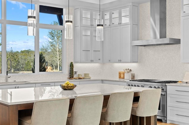 1047 Overlook Pkwy, Horseshoe Bay, TX 78657 - kitchen featuring wall chimney exhaust hood, stainless steel range, a kitchen island, backsplash, and a breakfast bar