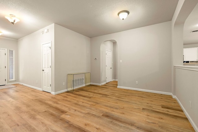 10804 N Canoa Hills Trl, Austin, TX 78717 - spare room with arched walkways, light wood-type flooring, baseboards, and a textured ceiling