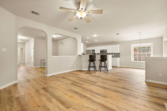 10804 N Canoa Hills Trl, Austin, TX 78717 - living room featuring arched walkways, ceiling fan, baseboards, and light wood finished floors