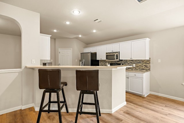 10804 N Canoa Hills Trl, Austin, TX 78717 - kitchen featuring appliances with stainless steel finishes, a kitchen bar, white cabinetry, a peninsula, and recessed lighting