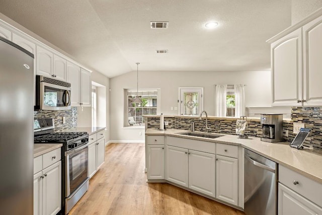 10804 N Canoa Hills Trl, Austin, TX 78717 - kitchen with appliances with stainless steel finishes, a sink, a peninsula, backsplash, and white cabinets