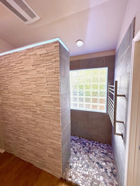 10804 N Canoa Hills Trl, Austin, TX 78717 - bathroom with a walk in shower, a towel warmer, and wood finished floors