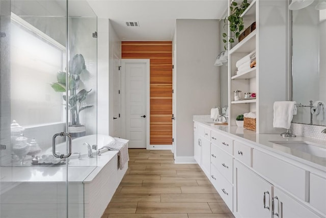 12404 Cardinal Flower Dr, Austin, TX 78739 - full bathroom with vanity, a shower stall, a garden tub, and wood finished floors