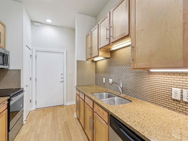 2931 E 12th St Unit 206, Austin, TX 78702 - kitchen with appliances with stainless steel finishes, a sink, tasteful backsplash, light stone counters, and light wood-type flooring