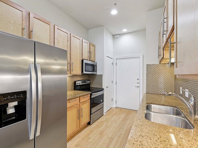 2931 E 12th St Unit 206, Austin, TX 78702 - kitchen featuring appliances with stainless steel finishes, a sink, light brown cabinetry, tasteful backsplash, and light stone countertops