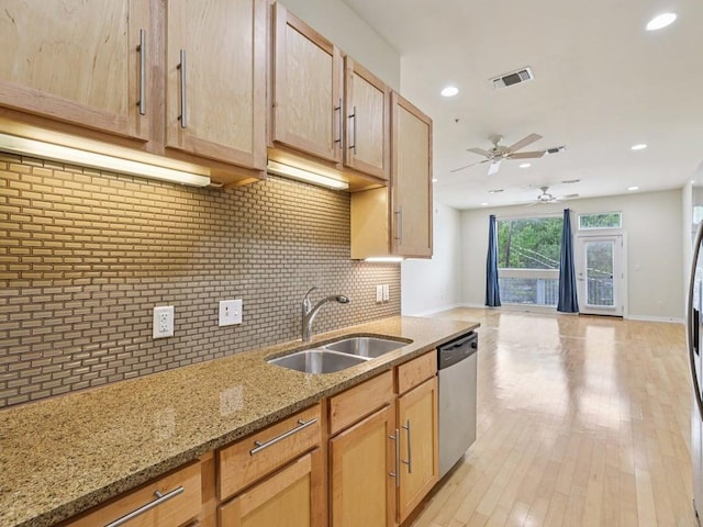 2931 E 12th St Unit 206, Austin, TX 78702 - kitchen featuring stainless steel dishwasher, a sink, ceiling fan, backsplash, and light stone counters
